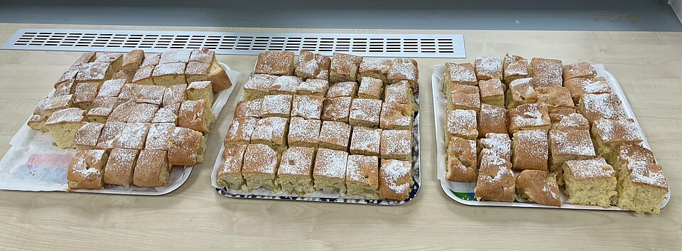Auf dem Bild sieht man drei Blech Apfelkuchen, die auf einem Tisch stehen.